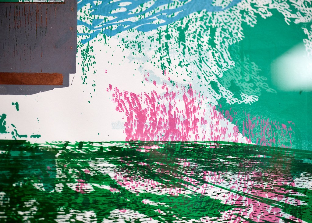 A close-up of a painting which includes pink and green shapes and textures