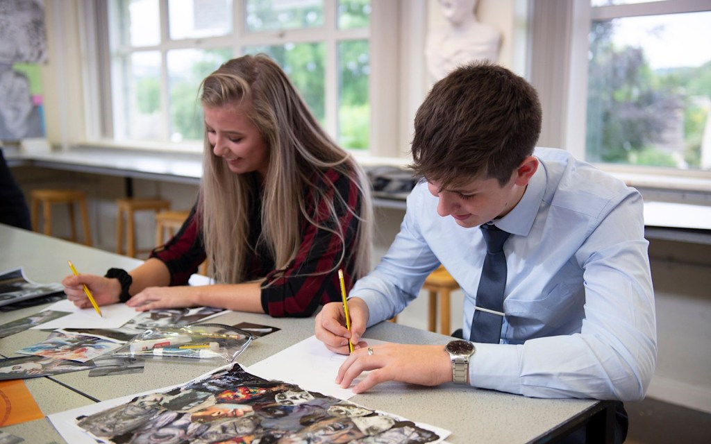 Two students writing on paper in a college