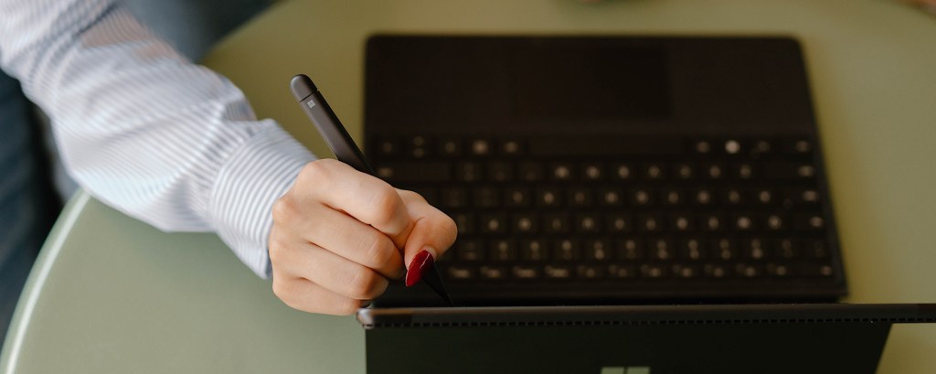 A student uses a pen to write on a tablet screen in a meeting