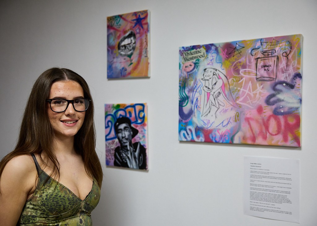 Three pieces of graffiti art and the artists stood in front of them