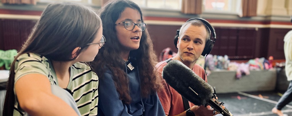 Three people are talking into a microphone for a podcast