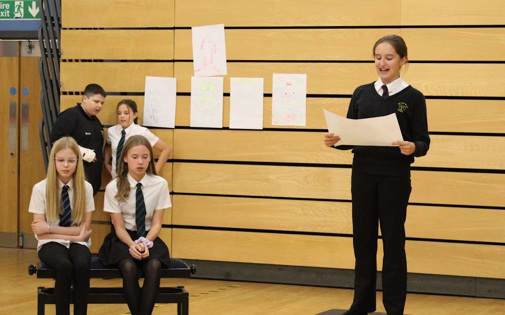 A student reads to the class from a piece of paper