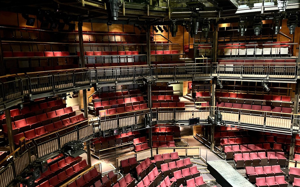A large auditorium of a theatre has red seats and balconies