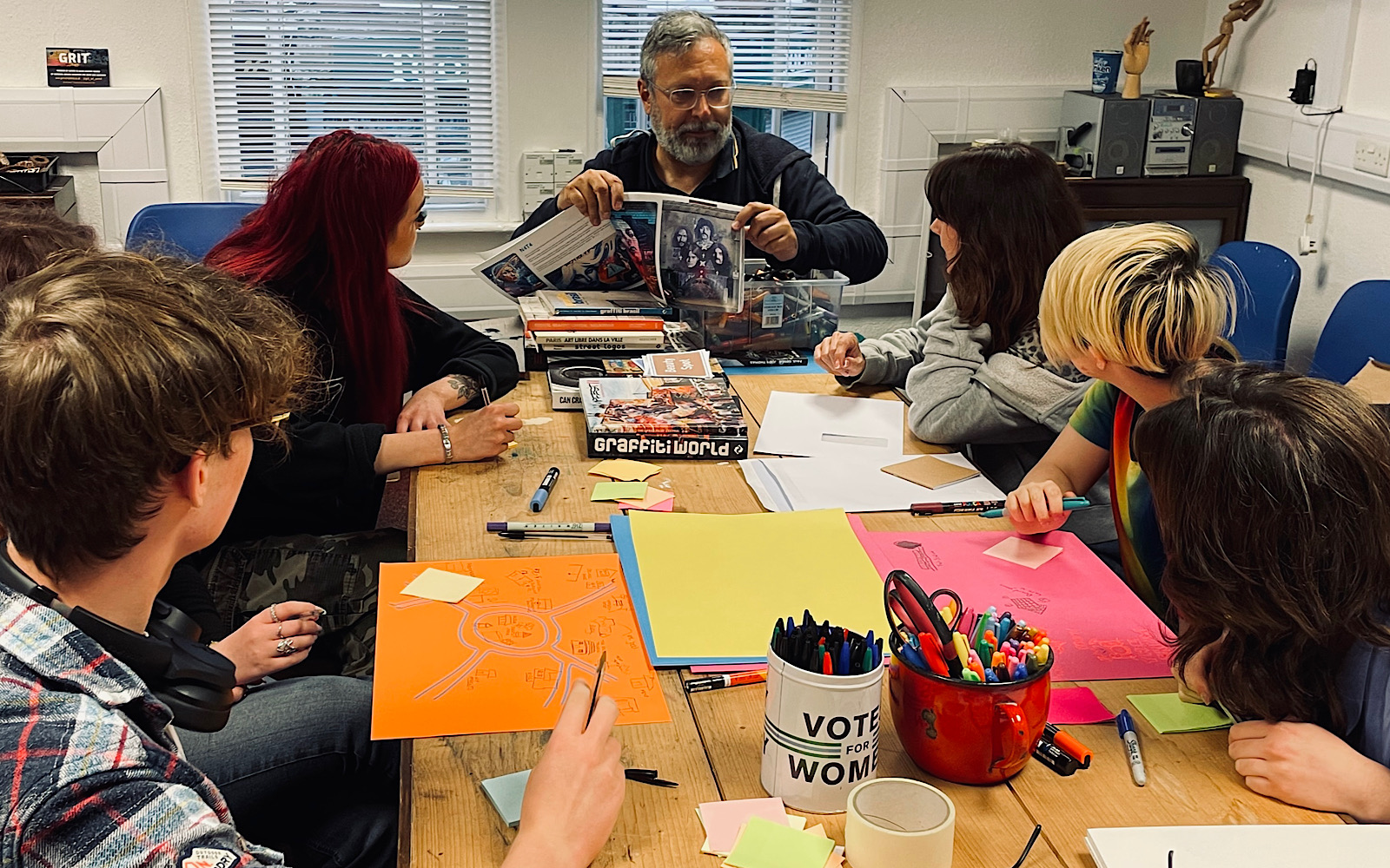 A group leader shows six young artists some books about graffiti