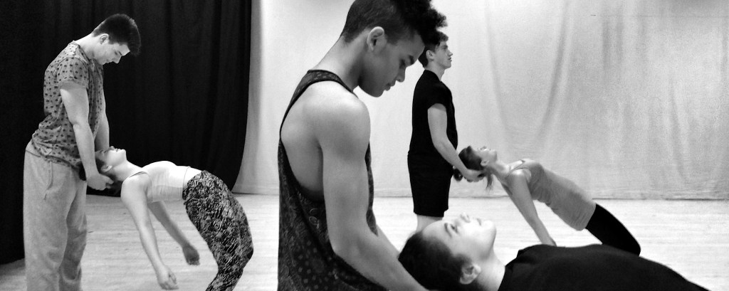 Dancer in a workshop hold the heads of other dancers who lean backwards