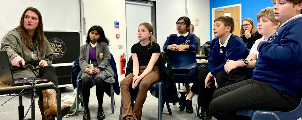 Students sit in a classroom looking at the front of the room