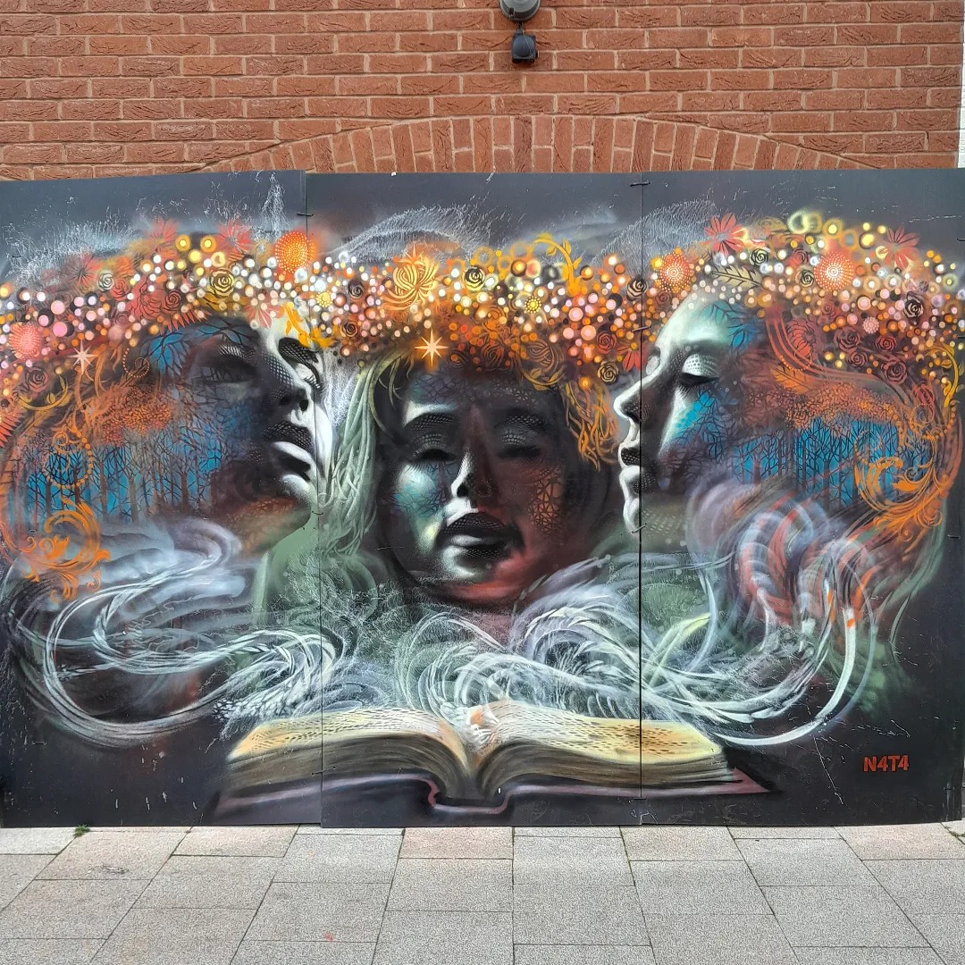 Street art shows three faces emerging from an open book