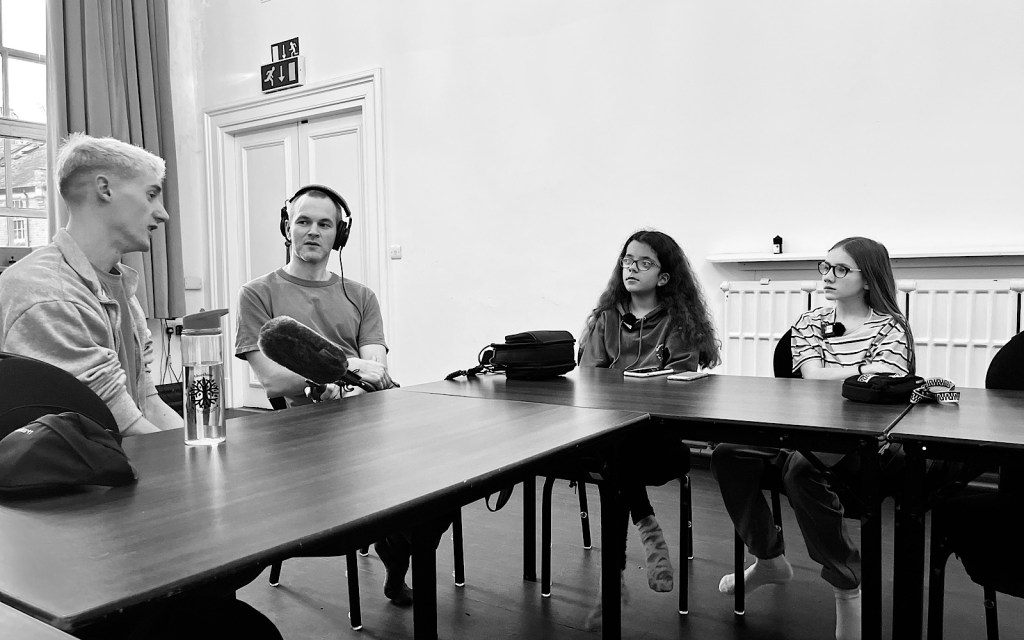 Four people sit at a table and record a podcast interview