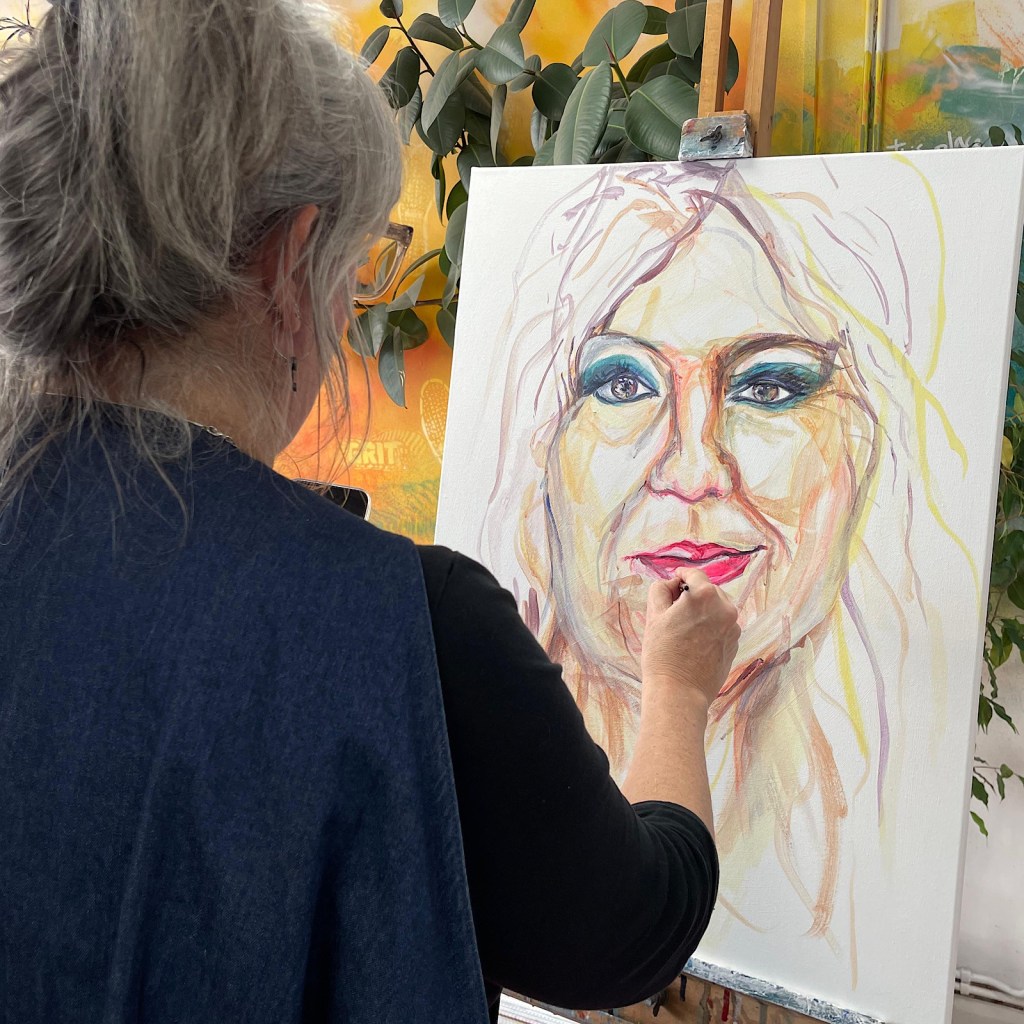 An artist paints a face on a canvas