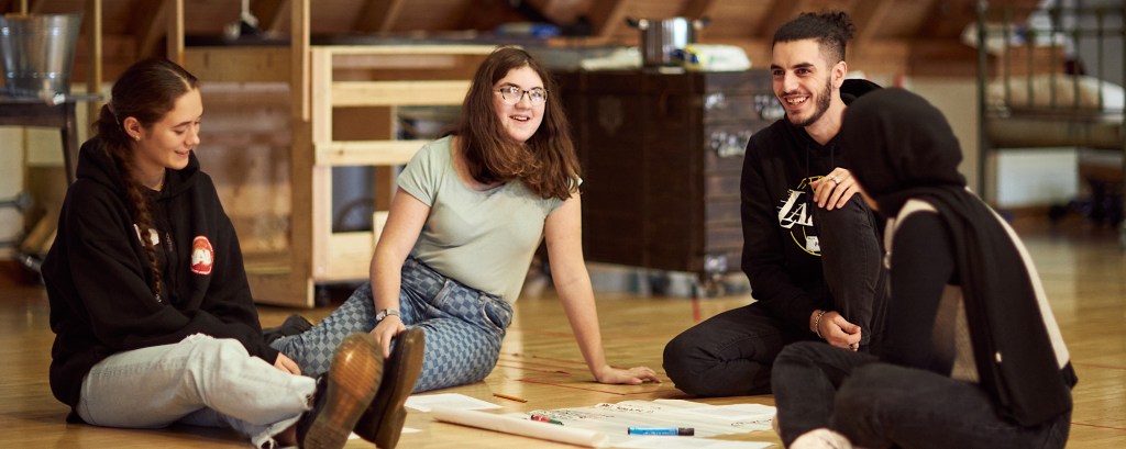 A group of four students sitting on the floor as part of a workshop