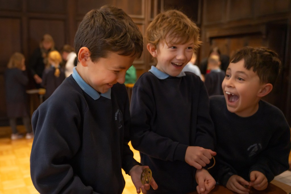 A group of children in school clothing are at a workshop and they are huddled together laughing