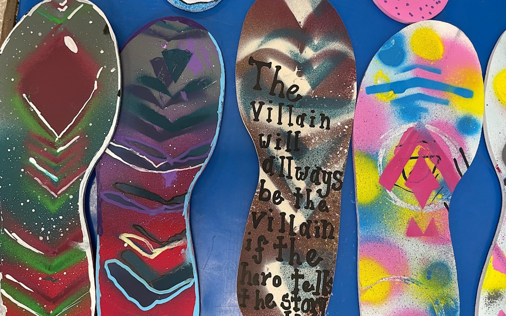 Pieces of art made by young people, and a quote on one of them reads ‘the villain will always been the villain if the hero tells the story’