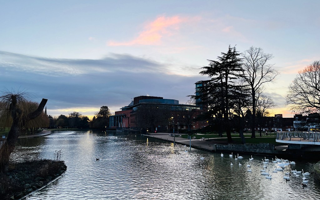A theatre sits by the river at sunset