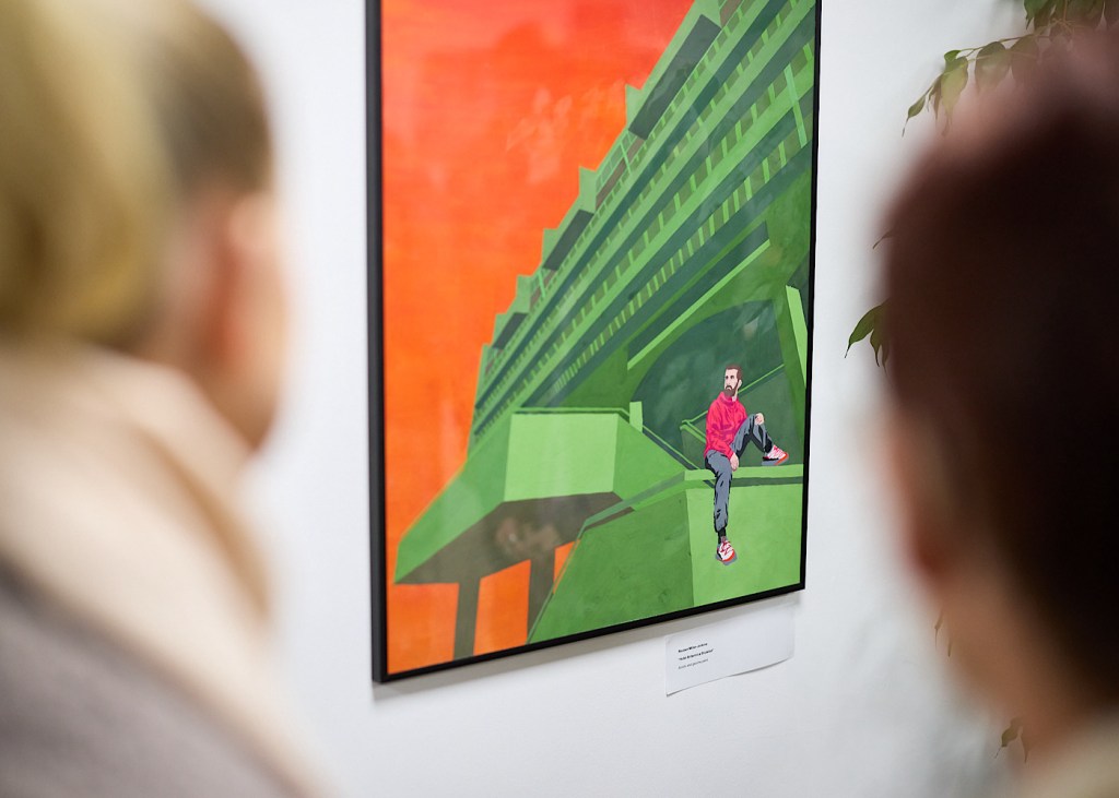 An illustrative piece of design is framed and shows someone sitting on a green building