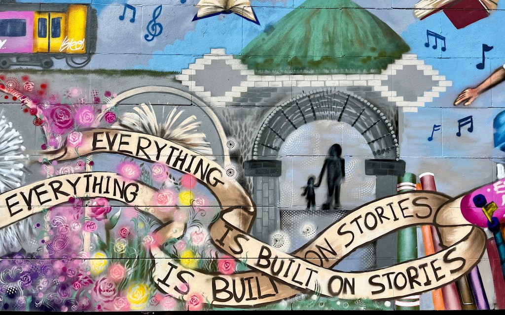 A close up of a street art mural and the phrase ‘everything is built on stories’