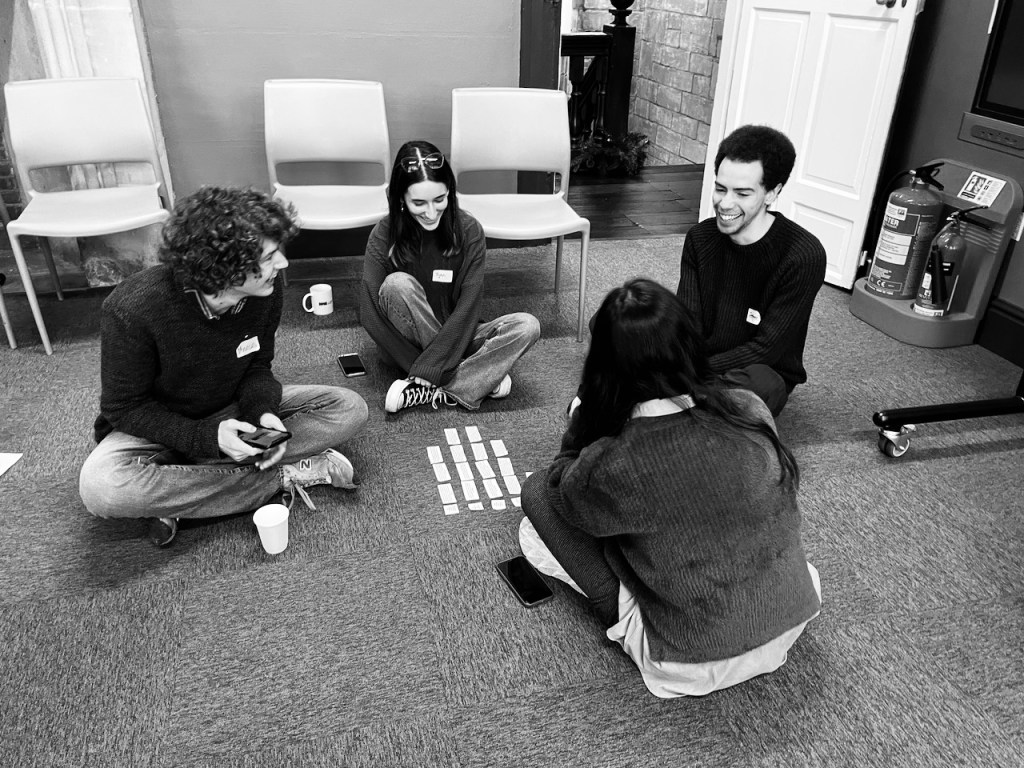 A group of four students sit on the floor and read notes