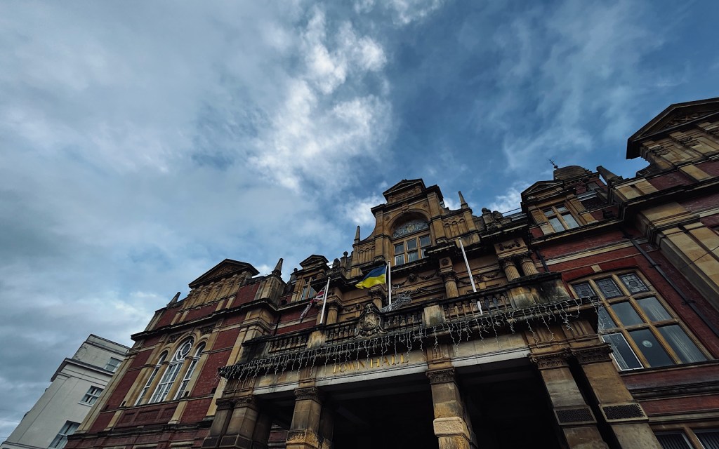 A large red brick building against a bright blue cloudy sky