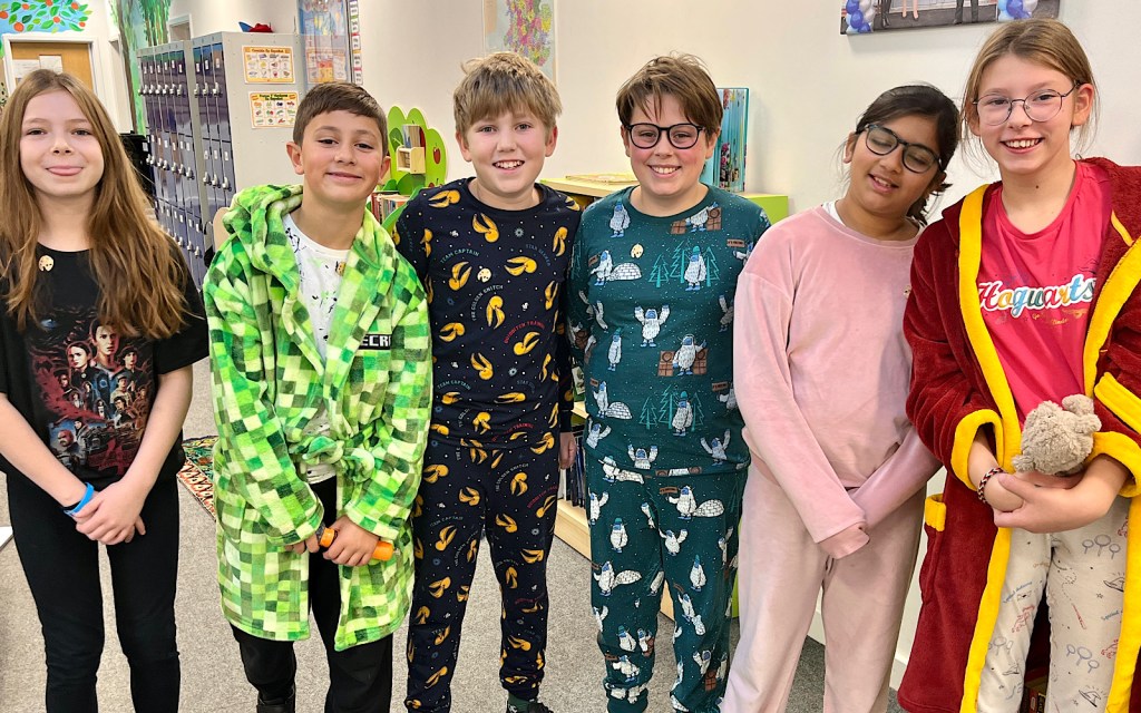 A group of six students huddle together to smile to the camera