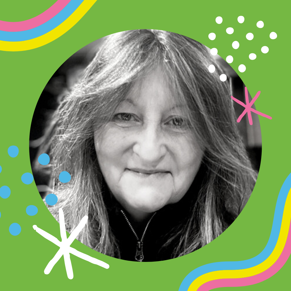 The face of Tracey Manning – an individual smiling to the camera wearing a black zip up hoodie and with shoulder length hair