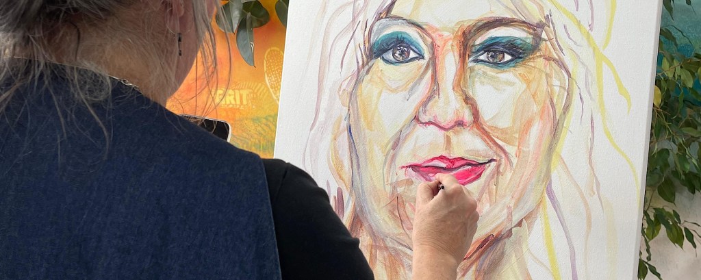 An artist paints a face on a canvas