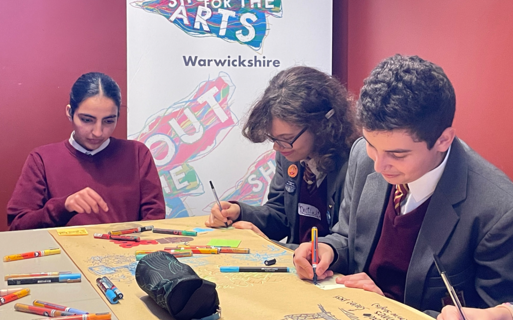 Three students write on a large piece of paper