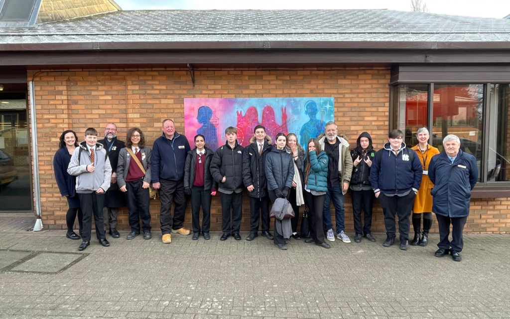 A group of young people stand in front of their mural